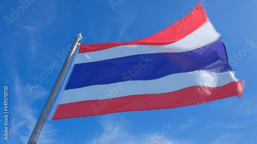 Thai flag waves in slow motion with a blue sky in the background 