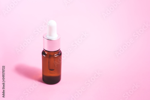 A glass dropper bottle on the pink background.