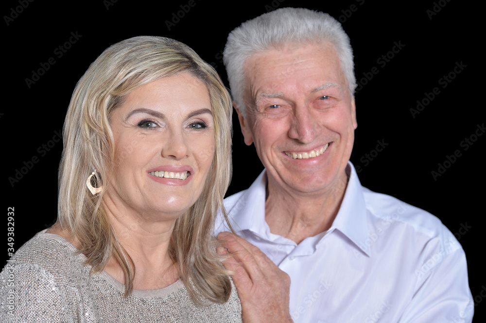 Happy senior couple posing on black background