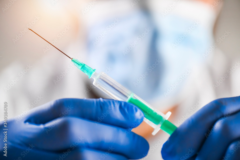 Syringe in doctor hands, medical injection in blue gloves, palm or fingers. Vaccine dose equipment with green needle. Drug or narcotic Liquid concept. Syringe in doctor hands, medical injection in blue gloves, palm or fingers. Vaccine dose equipment with green needle. Drug or narcotic Liquid concept.