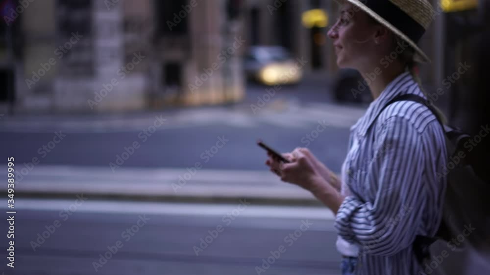 Young woman tourist walking on street and chatting in social networks on smartphone device using 4G internet.Female traveler typing text message on mobile phone during trip in new city
