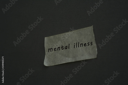 Mental illness concept. Close up "mental illness' words on the white tape. Gloomy, dark.