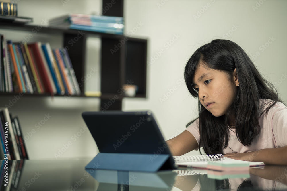 concentrated Mexican girl studying online with tablet at home doing homework concentrated Mexican girl studying online with tablet at home doing homework