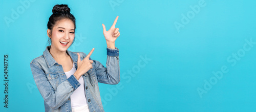 Fotografie Banner of Happy asian woman standing pointing hands to copyspace on blue background