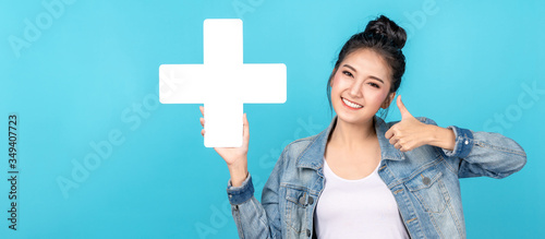 Banner of asian woman smiling, showing plus or add sign and thumb up on blue background. Cute asia girl wearing casual jeans shirt and showing join sign for increse and more benefit concept photo
