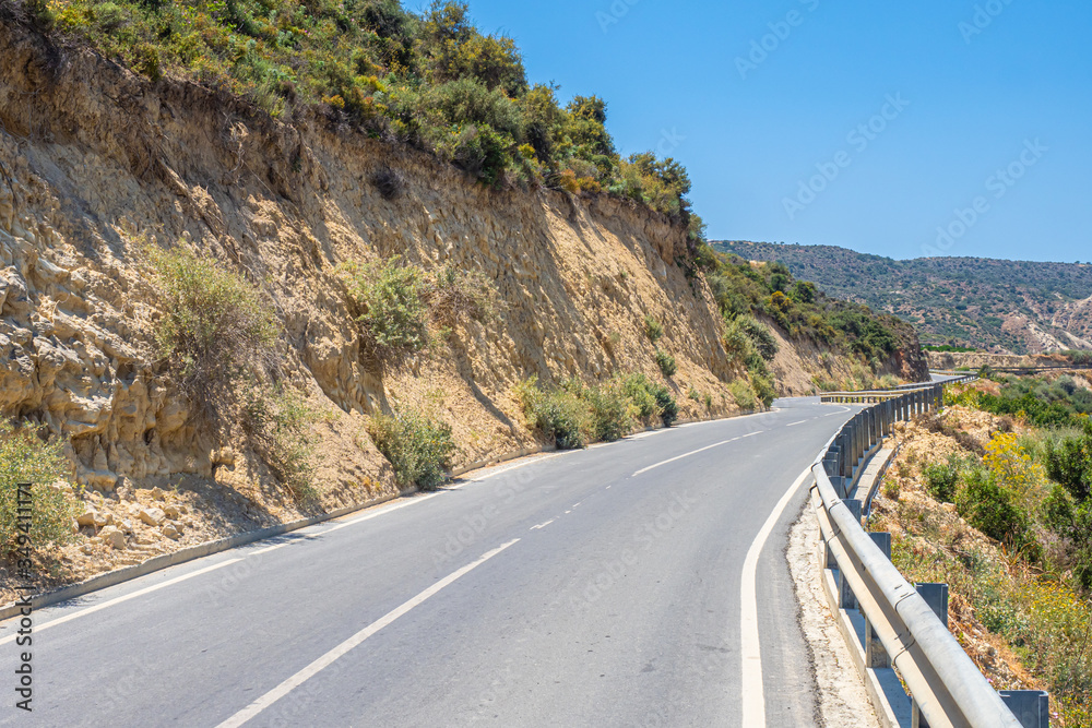The mountain road is empty. The road runs between the rocks. Travel to the Mediterranean coast. Travel by car. A trip to beautiful places on a summer day.