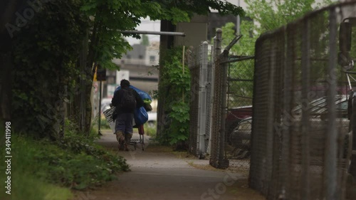 PORTLAND, OR - May 2020: Homeless man pushing a shopping cart away from the camera in slow motion