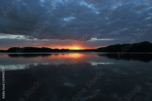 Colorful sunset under dramatic cloudscape reflected in the calm water of Paurotis Pond in Everglades National Park  Florida.