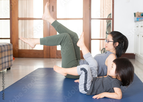 Asian girls and mothers are doing yoga by watching online yoga tutorial.