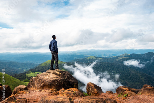 man isolated feeling the serene nature at hill top with amazing cloud layers in foreground photo