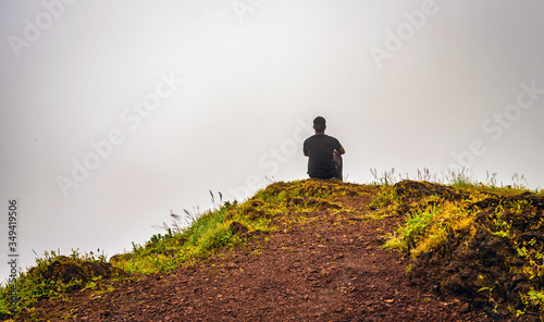 man isolated feeling the serene nature at hill top with amazing cloud layers in foreground © explorewithinfo