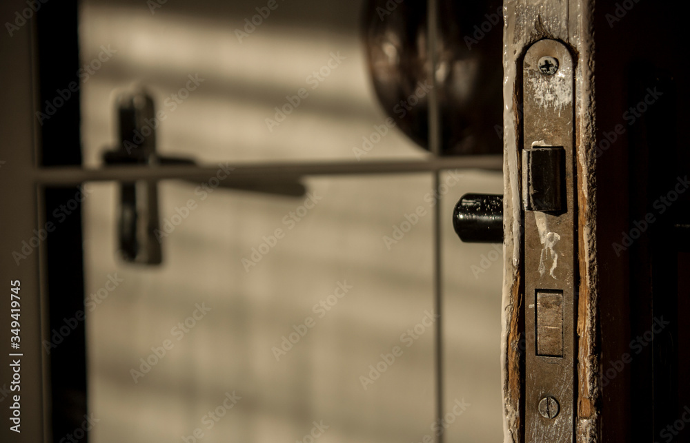 Old handle with a lock in a white door, reflected in the mirror. Peeling paint. Pleasant light in the interior. Old handle with a lock in a white door, reflected in the mirror. Peeling paint. Pleasant light in the interior.