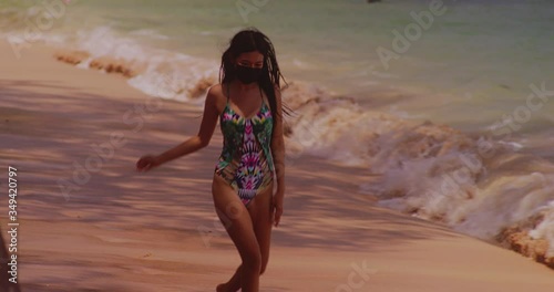 sexy girl wearing facemask running on a tropical sandy  beach photo