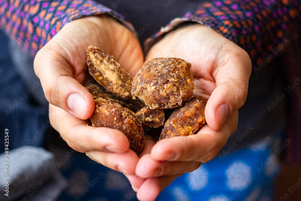 Jaggery or goor - asian brown unrefined cane or palm sugar made in India. Woman hands