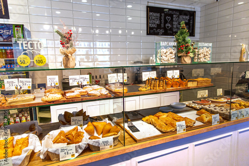 Baked baguettes and pies on showcase in bakery shop. Inscriptions in russian with the name baking