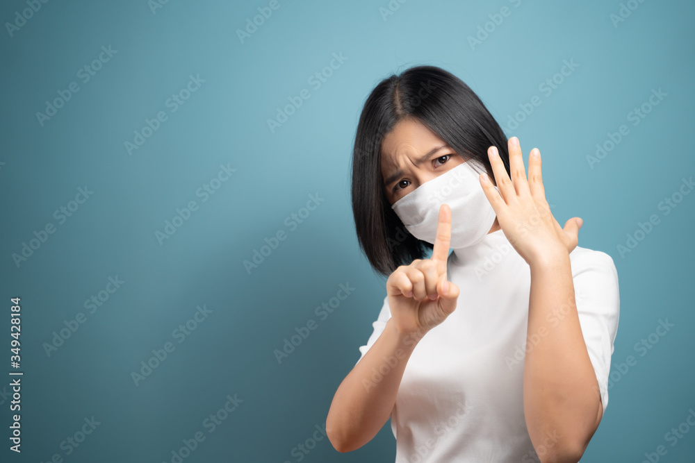 Don't Touch Your Face. Asian woman wearing hygiene mask showing hand stop sign and standing isolated over blue background. Health care concepts. Don't Touch Your Face. Asian woman wearing hygiene mask showing hand stop sign and standing isolated over blue background. Health care concepts.