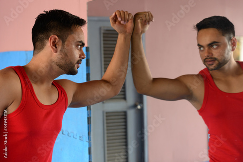 Foto Young bearded Indian man talking to the mirror for motivation at the gym