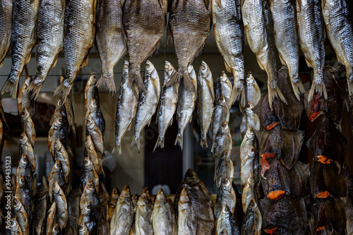A lot of dried fish hanging on the ropes. A delicacy on the market counter. Close-up.