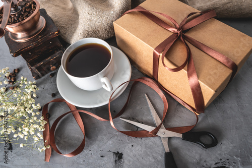 Foto Cup of freshly brewed black coffee, a gift box tied with brown ribbon, and a pair of scissors