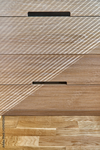 Wooden cupboard with drawers in daylight. Modern wooden furniture. Wooden texture