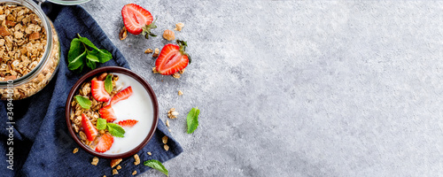 Food Background. Breakfast with yogurt, granola or muesli and strawberries on gray concrete table background. Top view, copy space, flat lay. Banner image for website, design