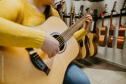 Young woman trying, buying new guitar in a instrument shop, instrumental concept photo