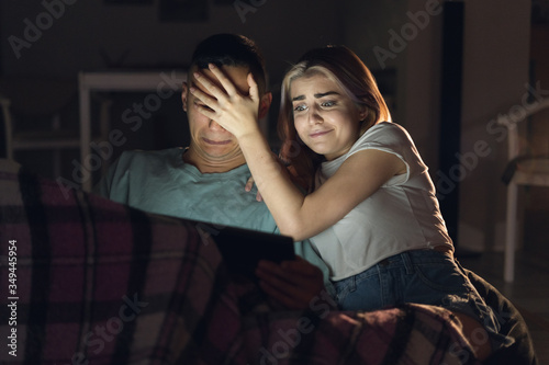 married couple sitting in the evening at home watching a movie. Cinema online. A woman closes her eyes to a man.