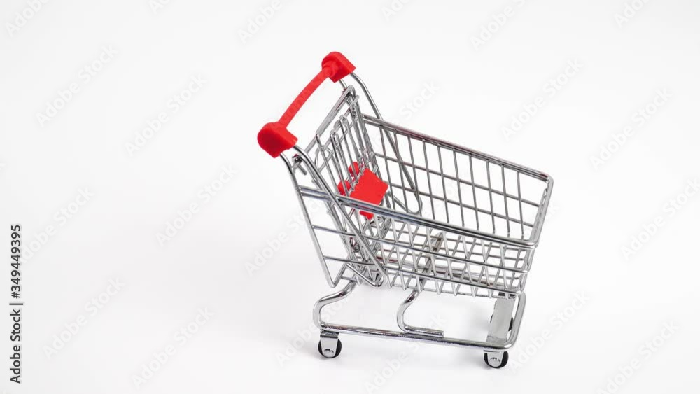Hand pushing miniature toy supermarket trolley. White background. Place for text. Shopping concept. Hand pushing miniature toy supermarket trolley. White background. Place for text. Shopping concept.