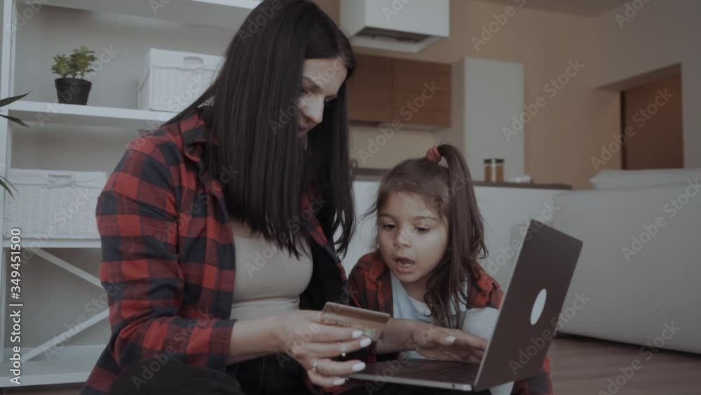 young mom with preschool cute daughter with laptop, making purchases in popular internet store, holding credit card for online payments. young mom with preschool cute daughter with laptop, making purchases in popular internet store, holding credit card for online payments.