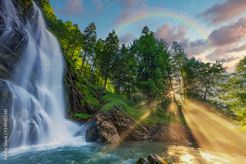 Fototapeta Naklejka Na Ścianę i Meble -  Magical waterfall with glowing sunrays and a rainbow