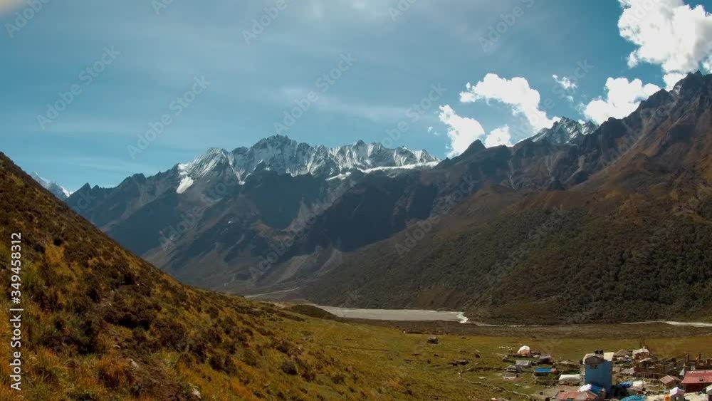 PAN of Mount Langtang Lirung range against the sun in remote Nepal. Kyanjin Gompa village can be seen on the foot of the hills. PAN of Mount Langtang Lirung range against the sun in remote Nepal. Kyanjin Gompa village can be seen on the foot of the hills.