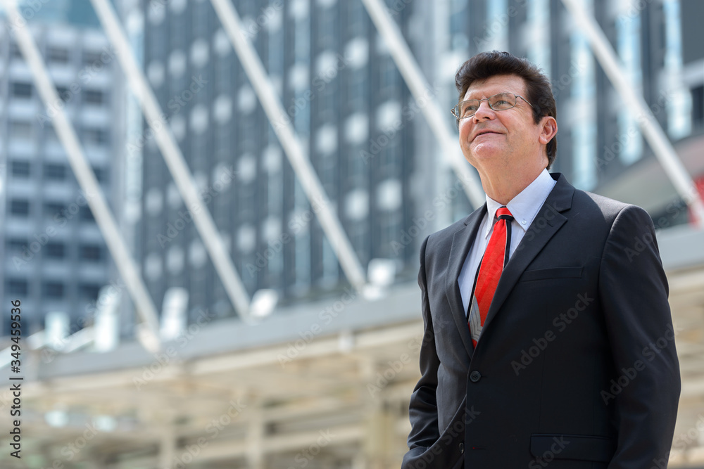 Mature happy businessman thinking in front of modern building at Bangkok city Mature happy businessman thinking in front of modern building at Bangkok city
