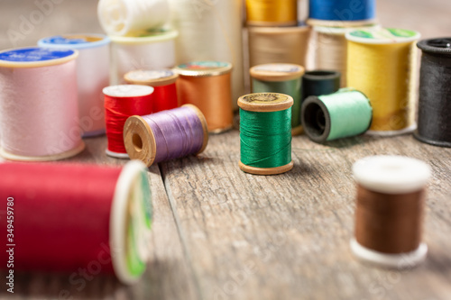 A closeup view of a variety of of thread spools in different colors, on a wooden surface.