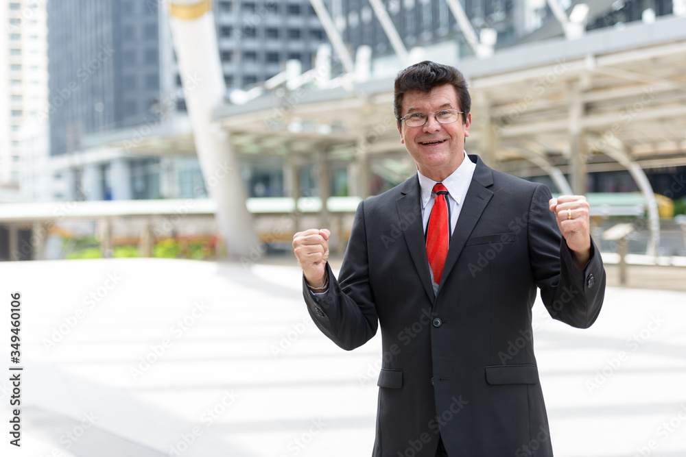 Mature happy businessman in front of modern building at Bangkok city Mature happy businessman in front of modern building at Bangkok city