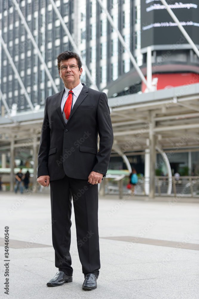 Mature handsome businessman in front of modern building at Bangkok city Mature handsome businessman in front of modern building at Bangkok city