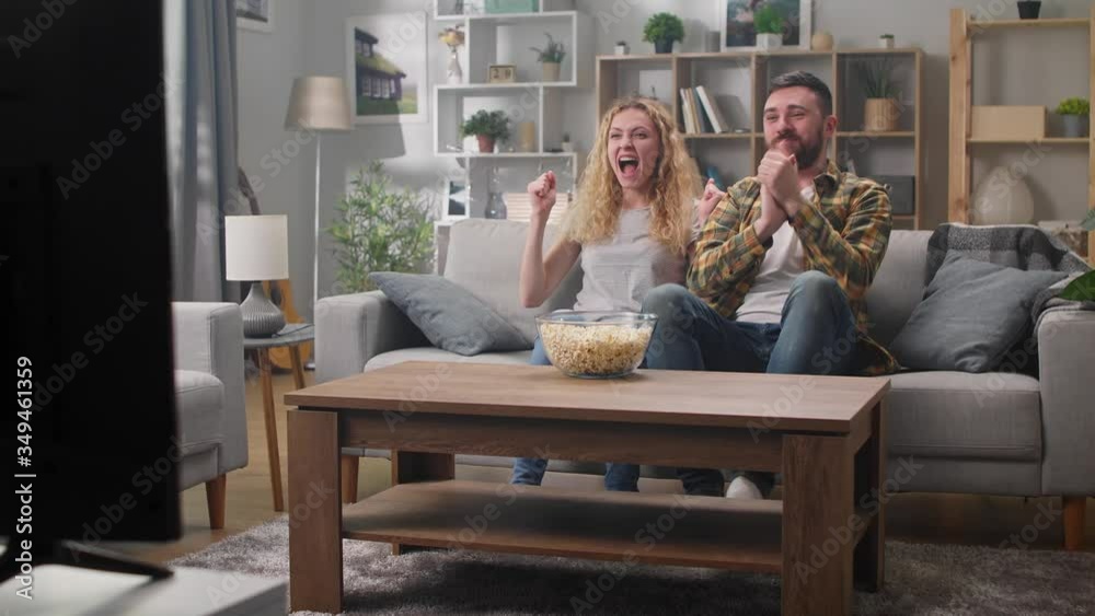 Couple watching sports on tv and rejoice at goal scored Couple watching sports on tv and rejoice at goal scored
