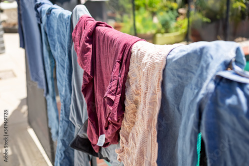 A view of several articles of clothing drying and hanging on a fence in a home backyard setting.