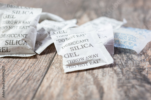 Fényképezés A closeup view of several silica gel packets, on a wooden surface