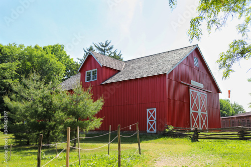 Fotografia A bright red barn in the green field in a day in summer