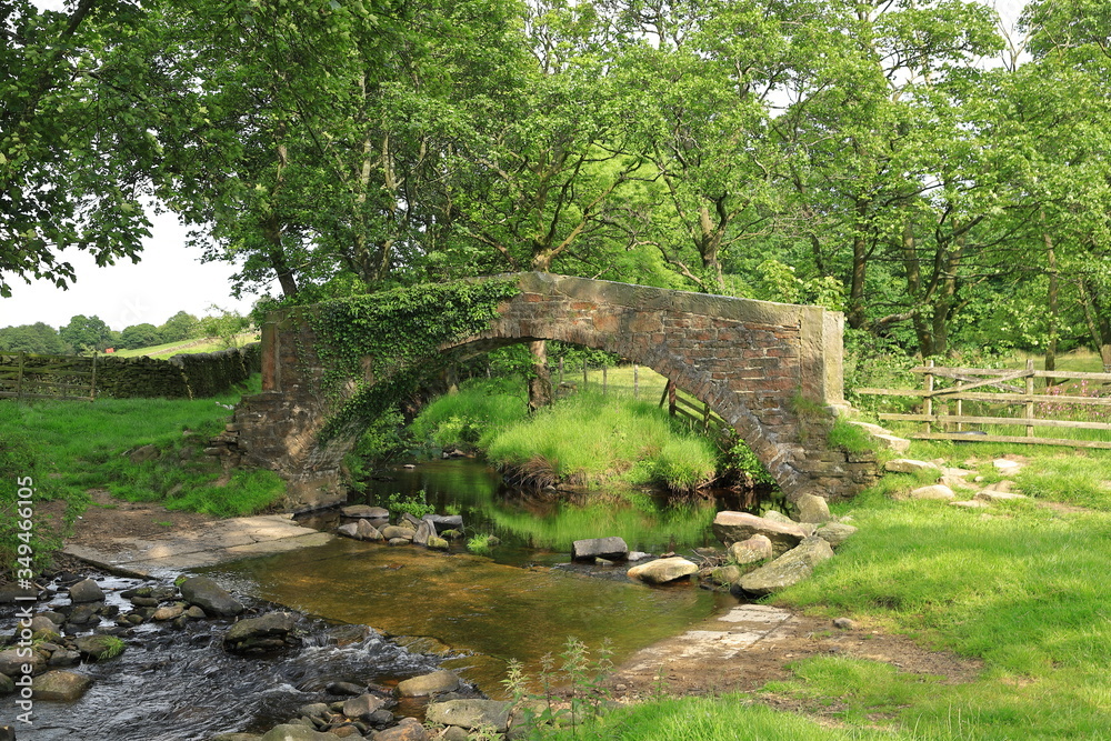 A stone bridge crosses a stream in the West Yorkshire countryside close to the village of Haworth in northern England.