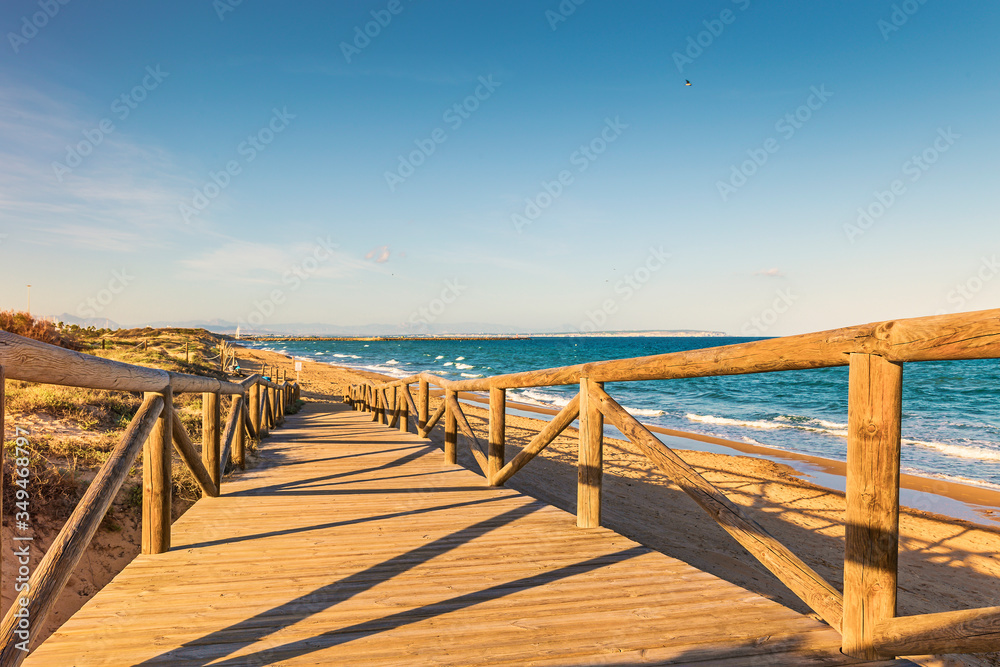 landscape of wooden footbridge to access the beach in summer . Guardamar, Alicante, Spain landscape of wooden footbridge to access the beach in summer . Guardamar, Alicante, Spain