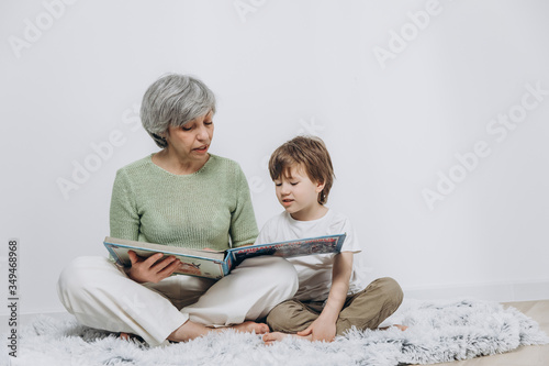 A little boy and his grandmother are having fun together against a light background