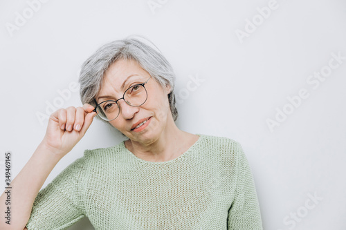 Elderly woman posing in a studio against a light background with copy space