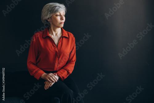 Elderly woman dressed in red against a dark background