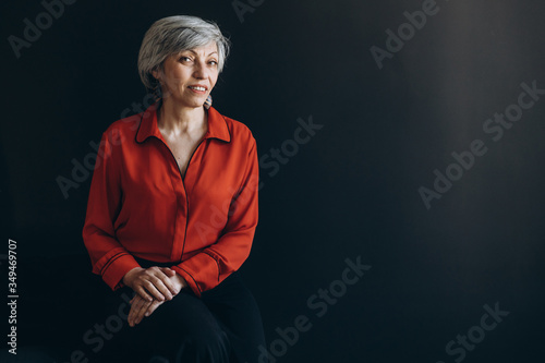 Elderly woman dressed in red against a dark background