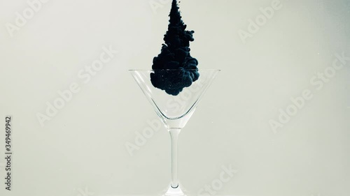 Cocktail glass in water with black paint project on it on a white background