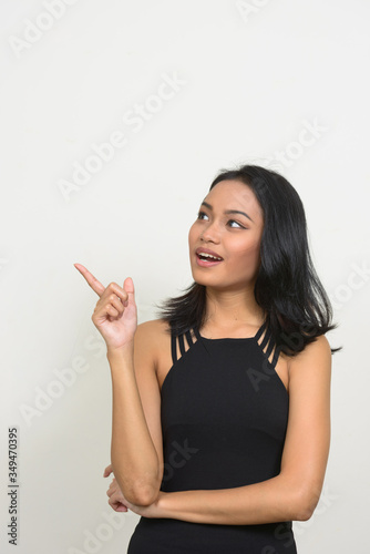 Portrait of happy young Asian businesswoman thinking and pointing up