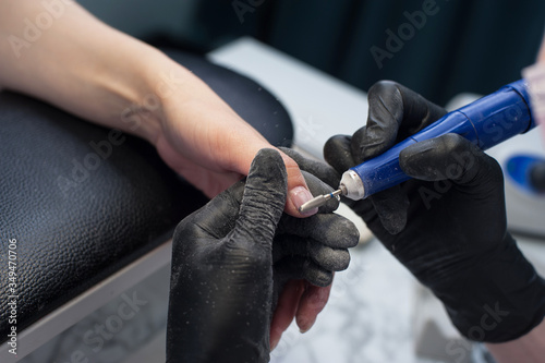 manicure, master saws off the nail gel Polish with a sander