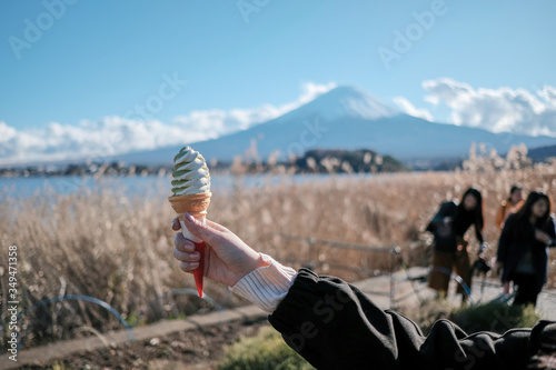 Green tea ice cream on female hand isolated from Mount Fuji background in sunshine day. Green tea ice cream with Mount Fuji and blue sky background.