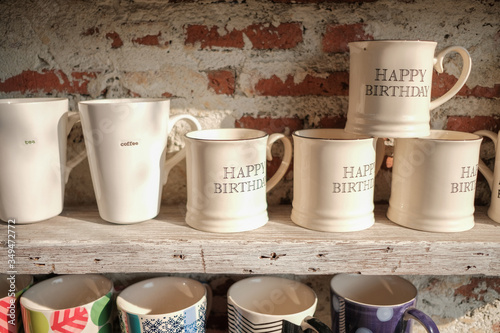 White mug cups placed on the wood shelves and red brick wall background